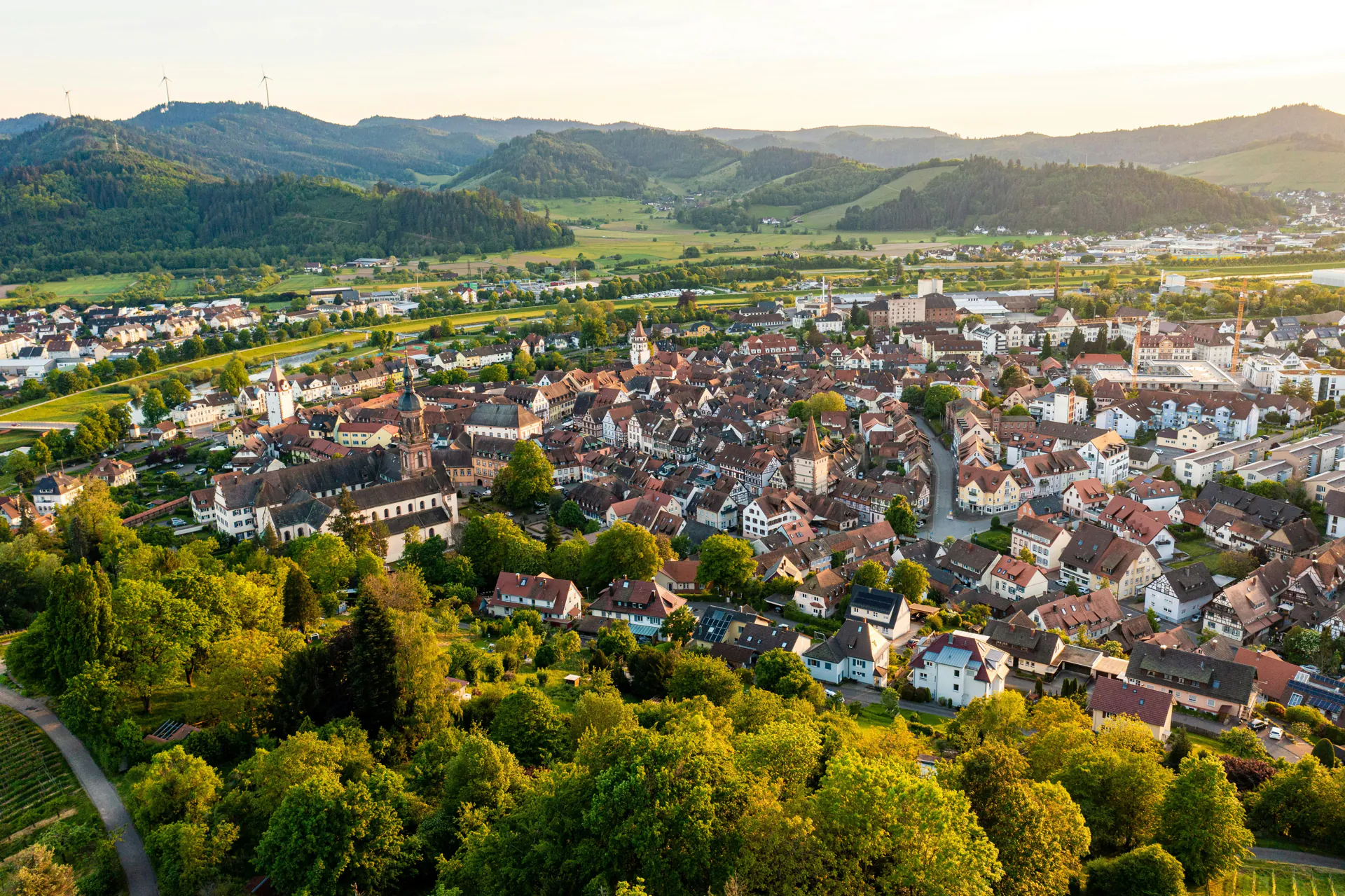 Aerial view of a small German town with wind turbines in the background at sunset